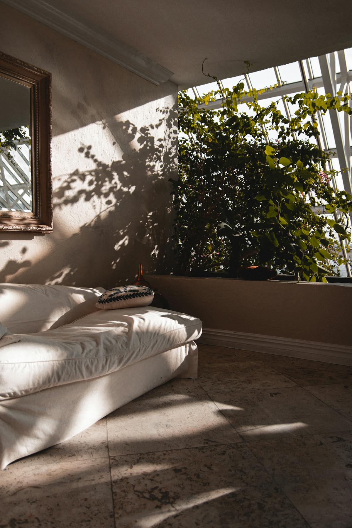 A sunlit corner with a soft cream sofa, dappled light through plants, and a calm welcoming feel — the kind of quiet, warm space a first counselling session is held in
