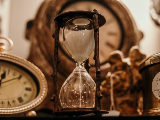 A warm sand-filled hourglass on a sunlit surface — a quiet image for thinking about how long therapy takes
